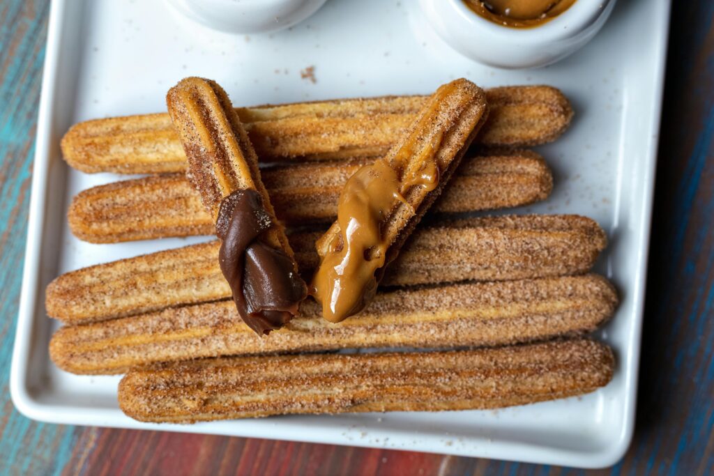 Top view of churros with chocolate and caramel dips on a plate.